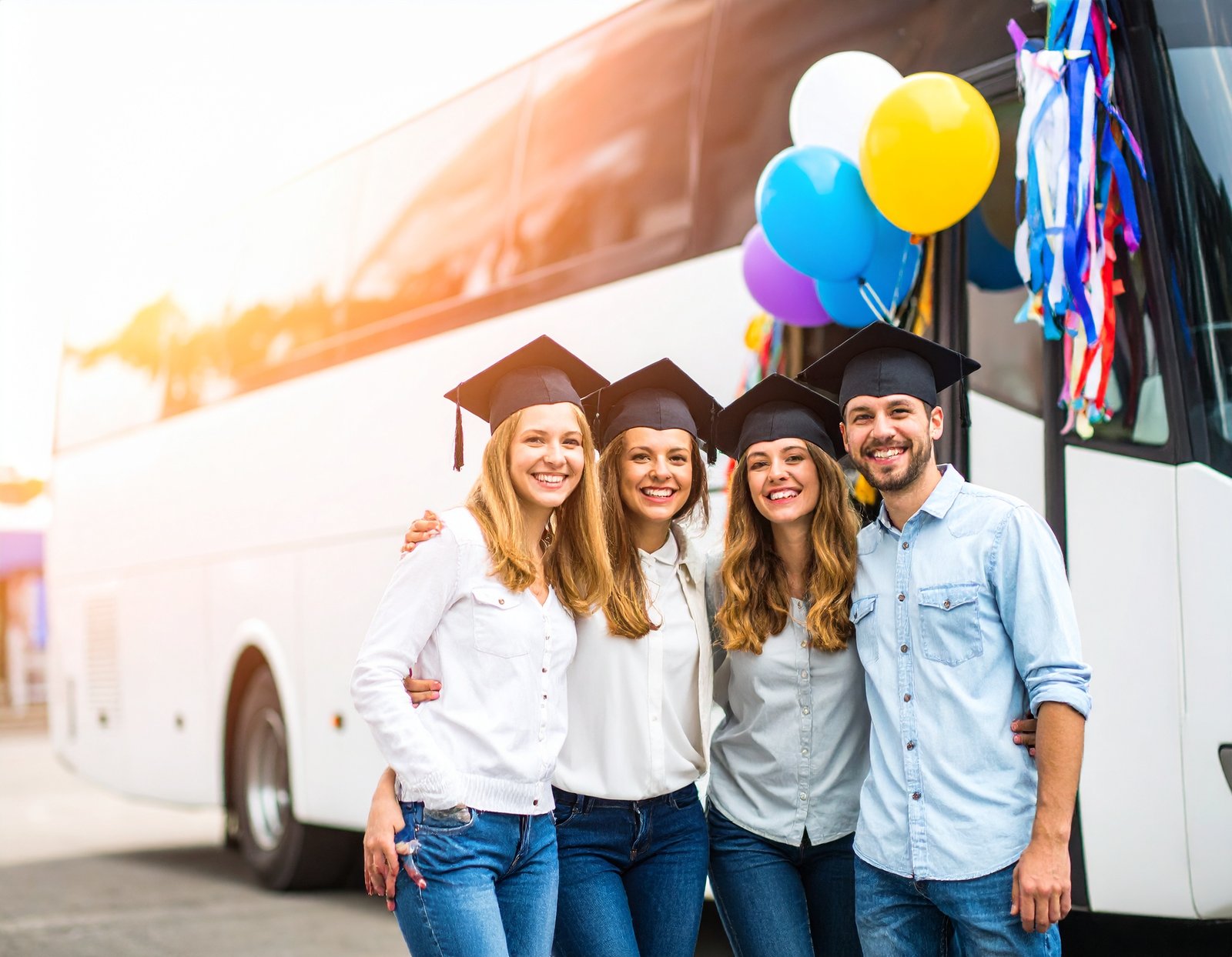 Graduates and family in front of a bus