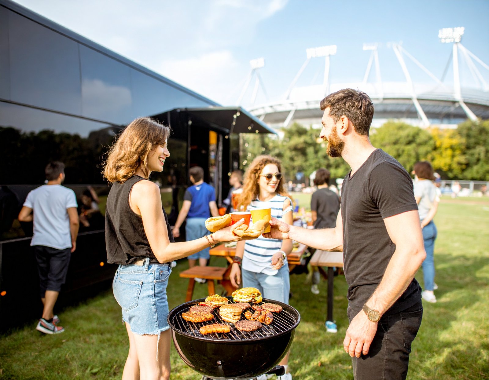 Sports fans tailgating near a luxury charter bus at a stadium